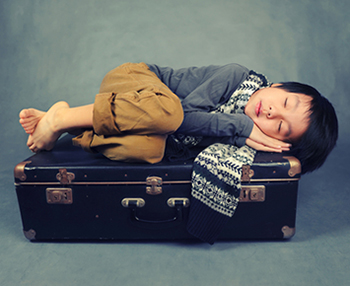 Child sleeping on suitcase