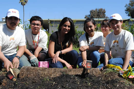 Emmanuelle Chriqui gardening with kids at Carson Senior High School, with an empty bag of Kellogg sludge compost