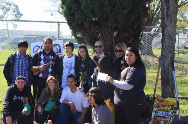 Emmanuelle Chriqui with Debbie Levin, Kathy Kellogg Johnson, and students at Carson Sr. High School with a bag of Kellogg's sludge-based product Gromulch