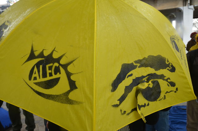 Yellow umbrella with eyes spray-painted on, with ALEC written in the pupil.