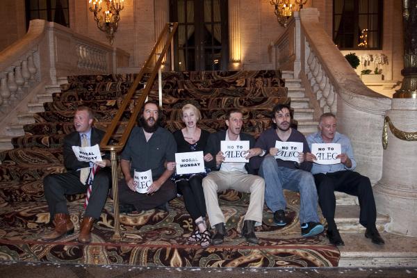 Six activists holding "no to alec" signs before being arrested