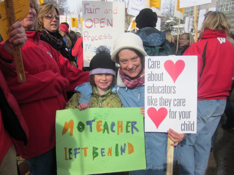 School was canceled today in Madison and many other Wisconsin communities. Seven-year-old Whitman holds a sign No Teacher Left Behind and stands with her Kindergarden teacher Mary Jo Yttri of Lapham Elementary School.